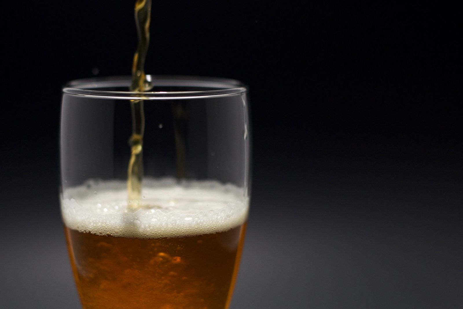 De la bière versée dans un verre, sur fond noir